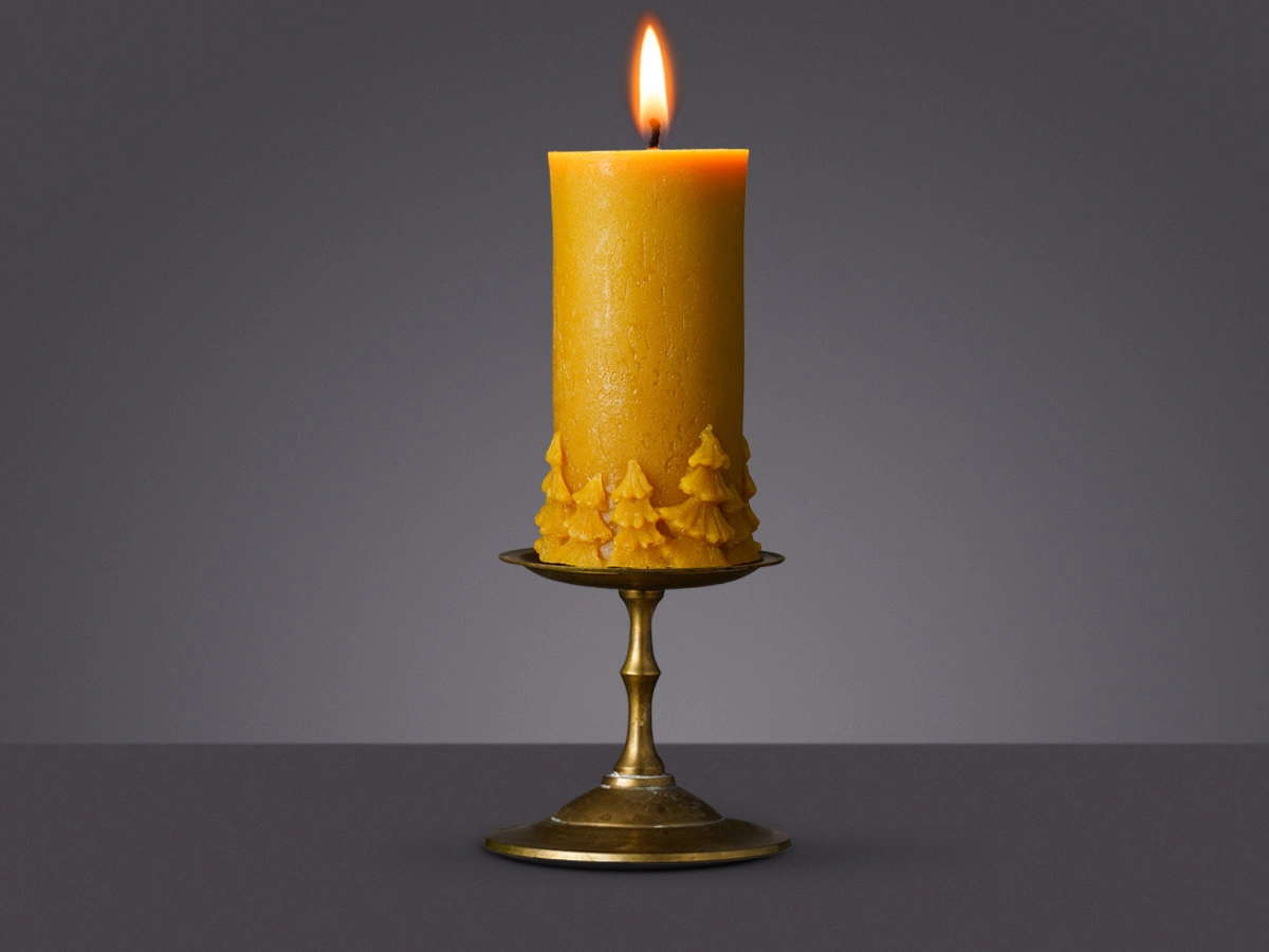 Świeca z wosku pszczelego w kształcie walca z choinkami wokół podstawy